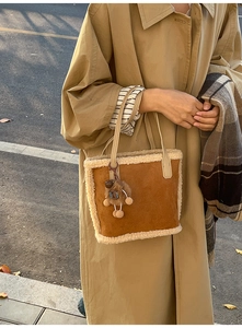 Détail du sac seau en daim marron avec bordure en peluche et pendentif animal doux