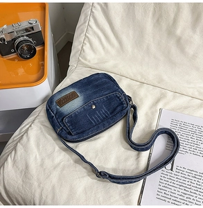 Detailed overhead view of vintage washed denim crossbody bag on white textured surface