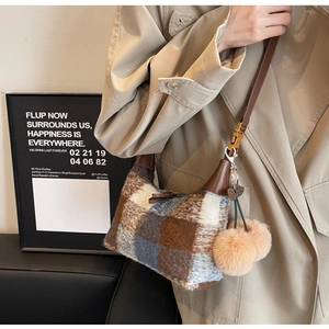 Detail der karierten Tweed-Schultertasche mit Kunstpelz-Bommeln und dunkelbraunem Leder