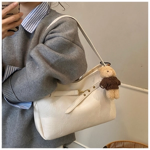 Détail du sac à épaule en cuir blanc avec boucle dorée et breloque d'ours en peluche