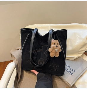 Détail d'un sac cabas en daim noir avec broderie de dessin animé et breloque ours