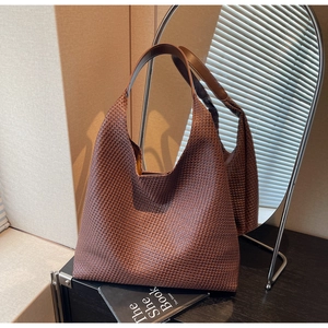 Detailed close-up of coffee brown woven leather tote bag texture reflected in a mirror