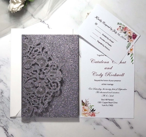 Macro detail of laser cut silver glitter wedding invitation set on white marble