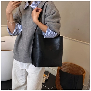 Borsa a secchiello nera minimalista indossata a tracolla per un look quotidiano