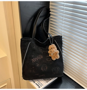 Gros plan d'un cabas en daim noir avec broderie de dessin animé et charm d'ours en peluche