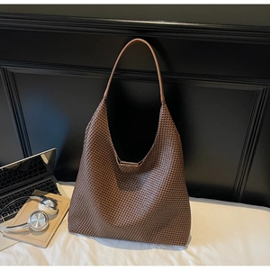 Detail of large brown woven hobo bag showing thick texture on a white surface