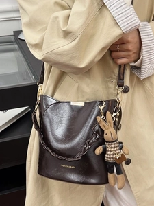 Deep brown oily leather bucket bag with woven handle and cute rabbit charm pendant