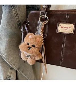 Close-up of a brown plush dog charm with pearl necklace attached to a leather tote bag