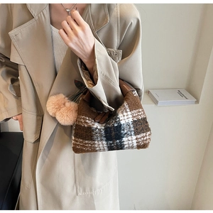 Detail einer Vintage-Plüschtasche mit Karomuster, rosa Anhänger und festem Tragegriff