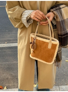 Vue de rue du sac cabas en daim marron avec garniture polaire et détail de pompon