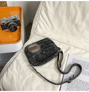 Flat lay of vintage washed denim crossbody bag with retro camera and leather patch detail