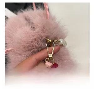 Dettaglio della fibbia dorata con perla bianca su una borsa in peluche rosa
