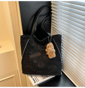 Détail du sac cabas en suédine noire avec broderies et pendentif d'ours en peluche