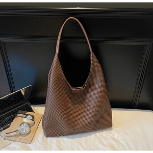 Close-up of woven texture on dark brown tote bag with office laptop and book props