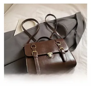 Detailed shot of a vintage dark brown leather messenger bag with double buckle straps and metal clasps