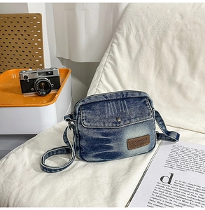 Détail d'un sac bandoulière en denim vintage avec logo en cuir et texture délavée