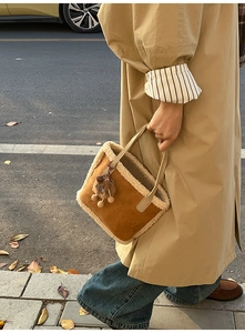 Détail du sac seau en daim marron avec bordure en fausse fourrure et pendentif peluche