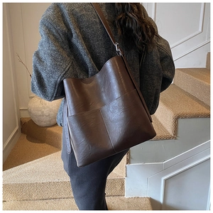 Vista dettagliata di una borsa a secchiello in pelle opaca marrone con tasche e tracolla