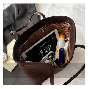 Top view of large brown tote bag interior with striped lining, fitting an iPad and cosmetics