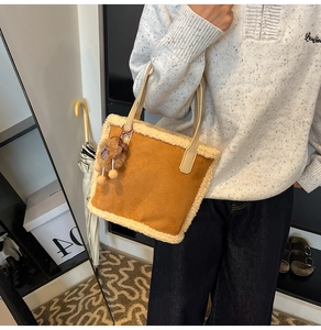 Détail du sac fourre-tout en daim marron avec bordure en peluche et un charmant pendentif