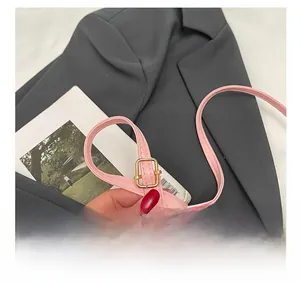 Dettaglio della tracolla regolabile in ecopelle rosa con fibbia dorata lucida