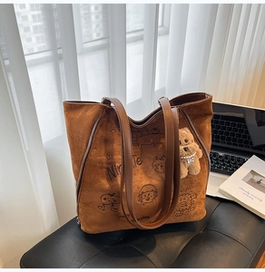 Détail d'un cabas en daim marron avec illustrations de dessins animés et charm en peluche
