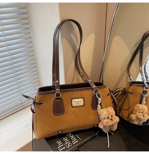 Detail of suede tote bag with brown plush bear charm and contrast leather trim