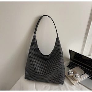 Detail of large houndstooth tote bag with leather strap next to lifestyle props