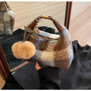 Nahaufnahme der Vintage-Plüschtasche mit Karomuster, Ledergriffen und Kirsch-Pompon-Anhängern