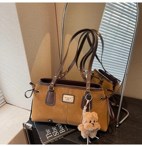 Detail of retro suede tote bag with brown leather trim and cute teddy bear pendant