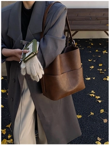 Borsa a secchiello vintage marrone abbinata a cappotto grigio in una strada autunnale