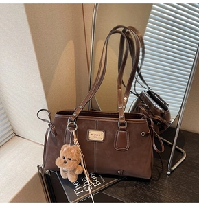 Detail of vintage brown suede tote bag with leather logo tag and plush dog charm
