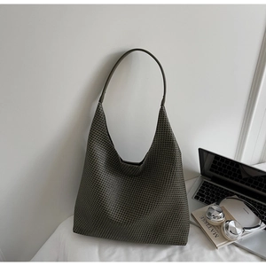 Detailed close-up of dark grey woven hobo bag with a laptop and books on white fabric