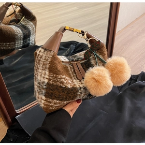 Detail der Retro-Plüschtasche mit Karomuster, Ledergriff und großem Kirsch-Anhänger