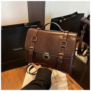 Detail of dark brown vintage messenger bag showing premium leather texture and metal buckle