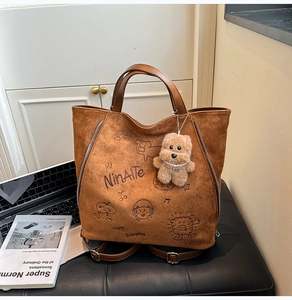 Détail du sac cabas en daim marron avec imprimés dessins animés et breloque peluche