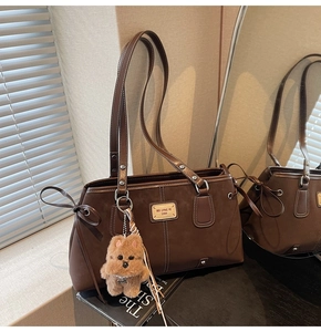 Macro view of dark brown faux suede tote bag with retro leather patch and puppy charm