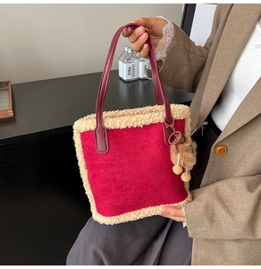Détail d'un sac seau en daim rouge avec bordure en fausse fourrure et breloque ours