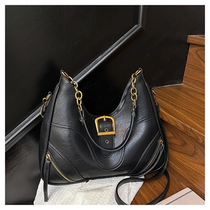 Detailaufnahme der schwarzen Leder-Tasche mit Goldkette und dekorativen Schnallenriemen