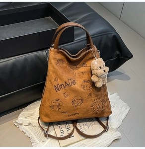 Détail du sac à dos en daim marron avec imprimés cartoon et breloque ours en peluche