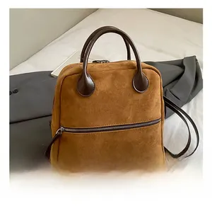 Détails d'un sac à dos en daim marron avec poignées en cuir et fermetures éclair en métal