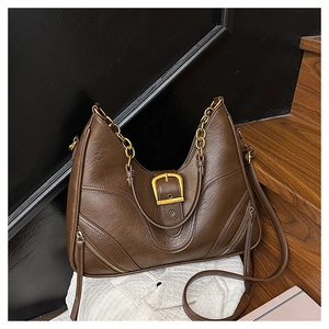 Detailansicht der dunkelbraunen Ledertasche mit goldener Schnalle und Kettengriff