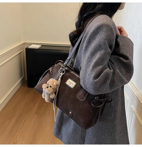 Detail of dark brown suede tote bag with a cute plush bear pendant and drawstring accents