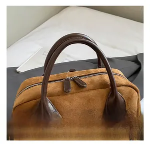 Gros plan d'un sac en daim marron avec poignées en cuir et fermetures éclair en argent