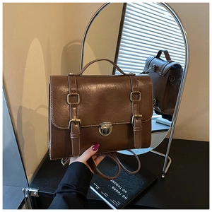 Close-up of vintage brown leather messenger bag with gold buckles and top handle