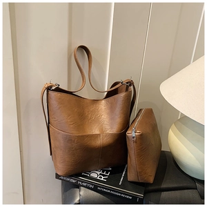 Set borsa a secchiello e pochette marrone su libri, in ecopelle martellata e hardware argento