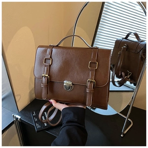 Detail shot of a brown vintage PU leather messenger bag with dual straps and metal lock