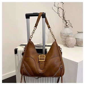 Detail einer braunen Ledertasche mit U-Nähten und einer Vintage-Goldkettenschulterriemen