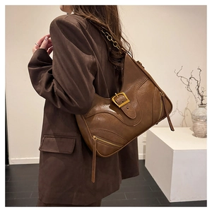 Detail der braunen Vintage-Ledertasche mit Metallschnalle und Ketten-Schulterriemen