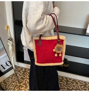 Détail du cabas en peluche rouge avec bordure en laine et breloque ours brun